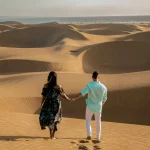 par går i sandklitterne i ørkenen i Maspalomas Gran Canaria, mænd og kvinder ser solopgang i ørkenen i Maspalomas Gran Canaria