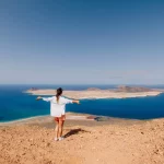 Glad resenär kvinna och naturskön utsiktspunkt till La Graciosa från ön Lanzarote