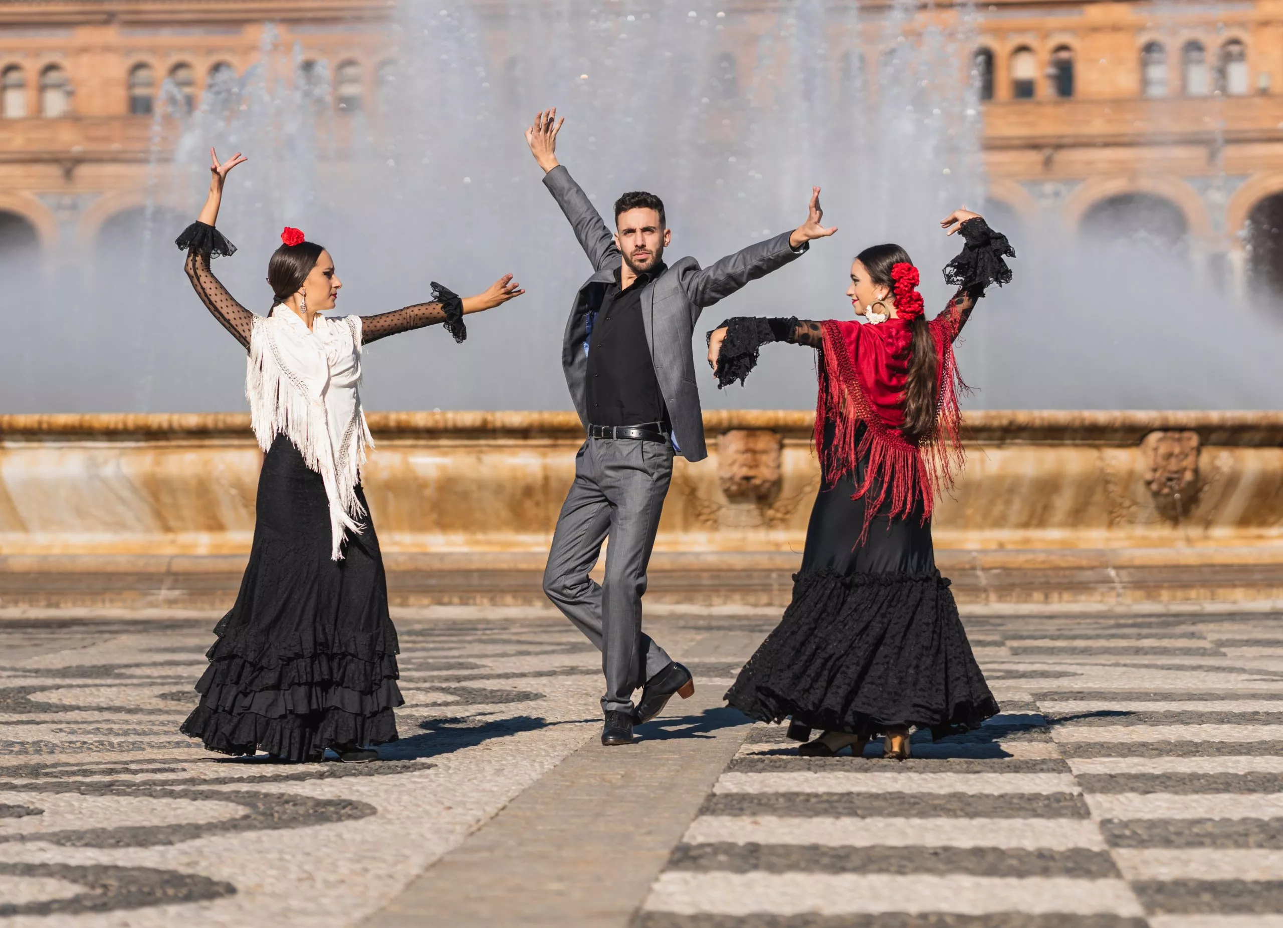 Three people with flamenco outfit dancing in the traditional square of Spain in Seville