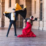 Hombre y mujer con traje de flamenca bailando a la sombra de la Plaza de España de Sevilla