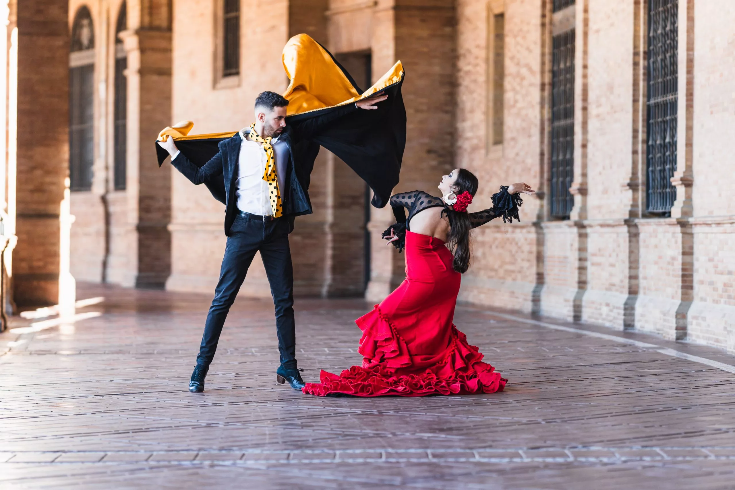 Man and woman in flamenco costume performing a dance on the shadow of the Spain Square in Seville