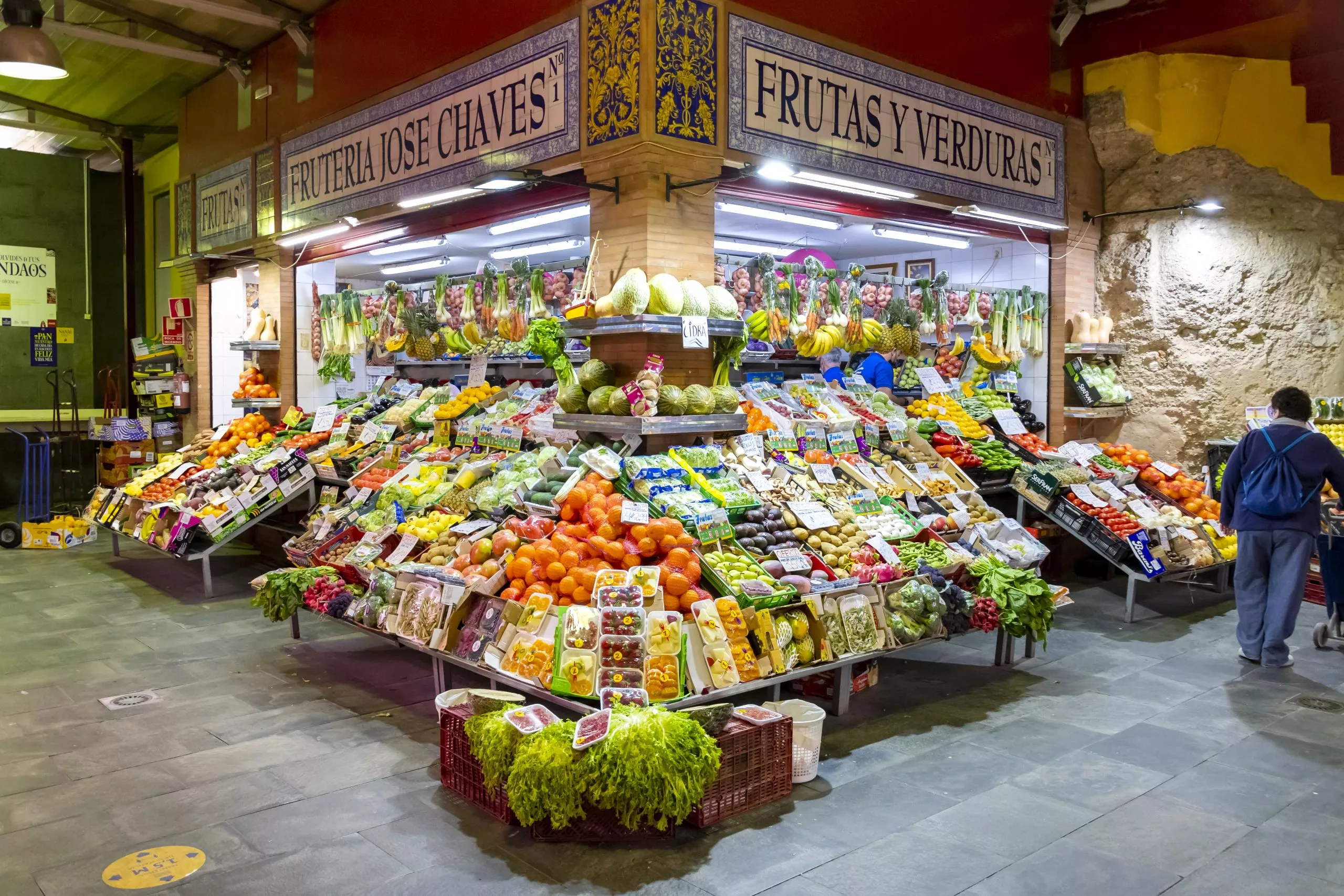 Fruit, vegetable, meat and produce vendors and stalls inside the colorful and vibrant Triana Market or Mercado di Triana in the historic Triana district of the Andalusian city of Seville Spain.